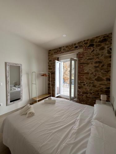 ein Schlafzimmer mit einem großen weißen Bett mit Ziegelwand in der Unterkunft Apartamentos Puerta los Castañares B in Constantina