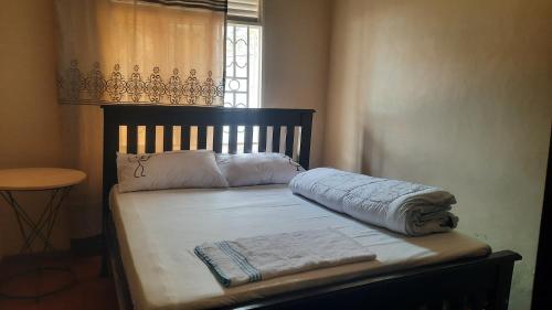 a bed with white sheets and pillows and a window at B40Motel in Kampala