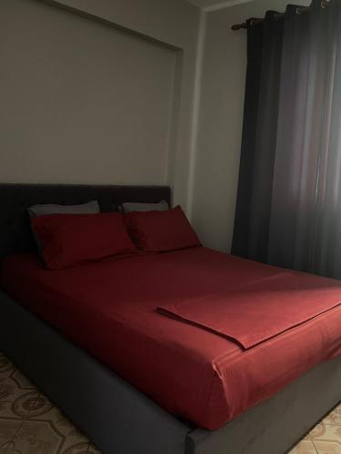 a red bed with red pillows in a bedroom at Ledi’s Home in Borsh