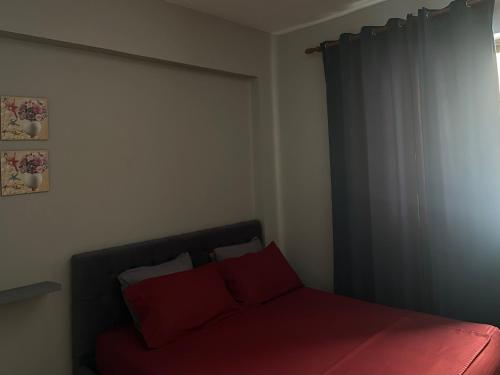 a bedroom with a bed with red pillows and a window at Ledi’s Home in Borsh