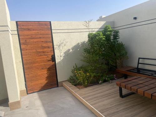 a wooden door on a balcony with a wooden bench at شاليهات العزيزية الفندقية in Buraydah