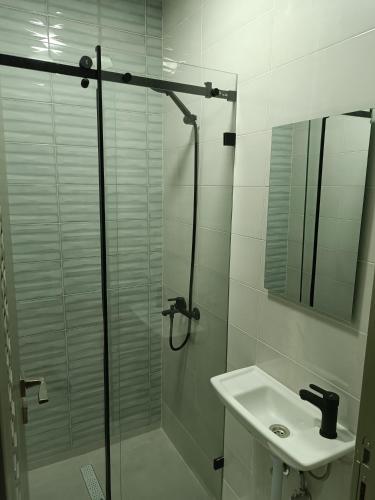 a white bathroom with a shower and a sink at Appart Résidence Sabrin in Fnidek