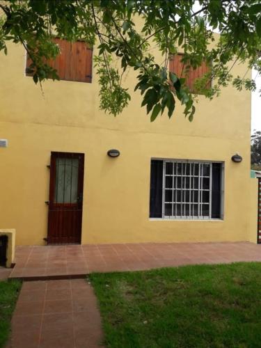 a yellow building with a door and a brick sidewalk at complejo lo de Elvira in Miramar