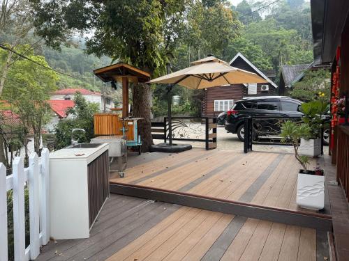 a wooden deck with an umbrella and a car at 郭媽媽包棟小木屋民宿 in Gukeng