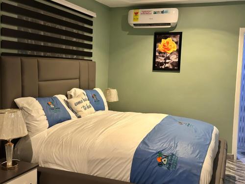 a bedroom with a bed with white sheets and blue pillows at Arek Condos Accra in Sotuom