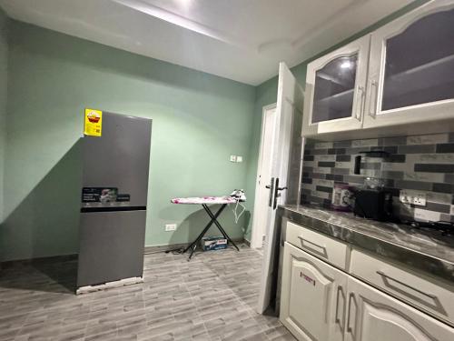 a kitchen with a refrigerator and a table in it at Arek Condos Accra in Sotuom