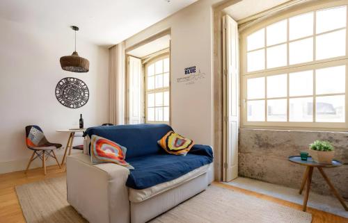 a living room with a blue couch and windows at Oporto Blue Almada - Deluxe Citycenter Flat in Porto