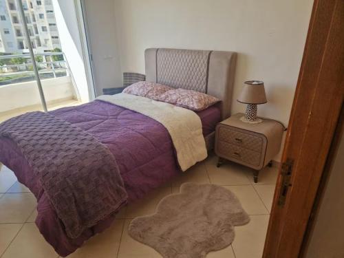 タンジェにあるMagnifique Appartement Vue sur Mer Tangerのベッドルーム(紫色のベッド1台、ナイトスタンド付)