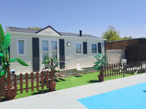 ein Haus mit einem Zaun neben einem Pool in der Unterkunft Casa prefabricada in El Casar de Escalona