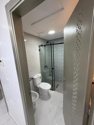 a bathroom with a toilet and a glass shower at Appart Résidence Sabrin in Fnidek