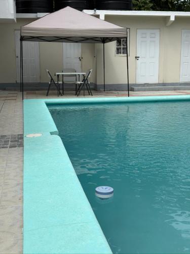a swimming pool with a table and an umbrella at Patch&Porch Cottage in Port Antonio