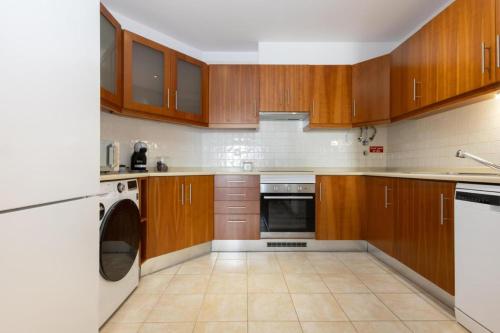 eine Küche mit Holzschränken, einer Waschmaschine und einem Trockner in der Unterkunft Porto de Abrigo in Burgau