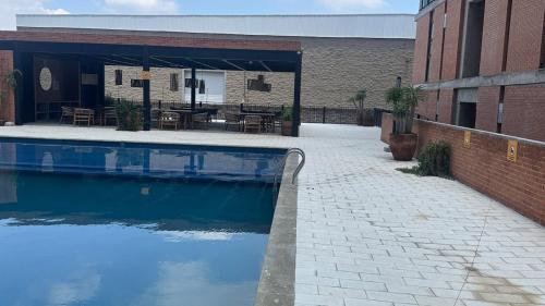a swimming pool in front of a building with a patio at Departamento 2 Recamaras en Torre Anuva con Alberca y Gym in Guadalajara