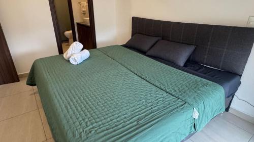a bed with a green comforter and a pair of towels on it at Departamento 2 Recamaras en Torre Anuva con Alberca y Gym in Guadalajara