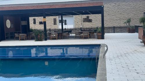 a pool with a patio with tables and chairs at Departamento 2 Recamaras en Torre Anuva con Alberca y Gym in Guadalajara