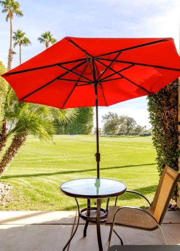 a table and a chair with a red umbrella at Desert Princess Serenity Suite in Cathedral City