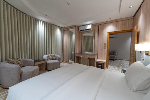 a bedroom with a large white bed and two chairs at السهم الذهبي للشقق المخدومة in Taif