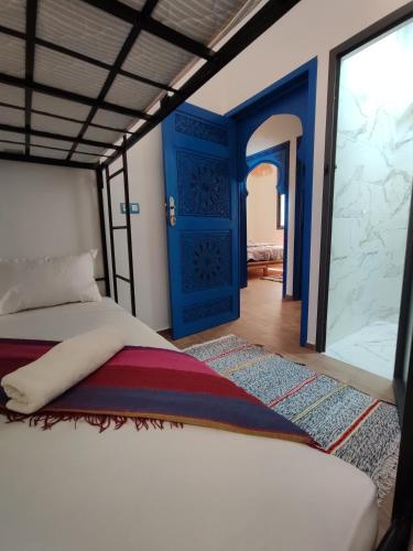 a bedroom with a bed and a blue door at Blue Pearl Surf House Morocco in Oulad Akkou