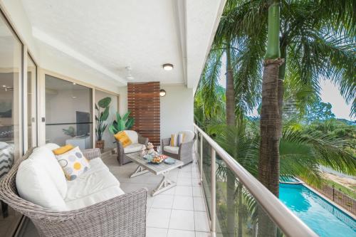Cet appartement dispose d'un balcon avec une piscine et des palmiers. dans l'établissement Phil's Place on Airlie, à Airlie Beach