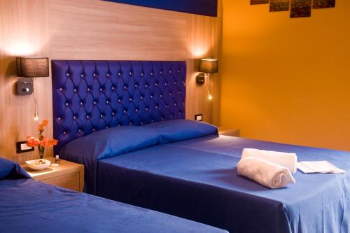 a bedroom with two beds with blue sheets and yellow walls at B&B Liberty in Messina