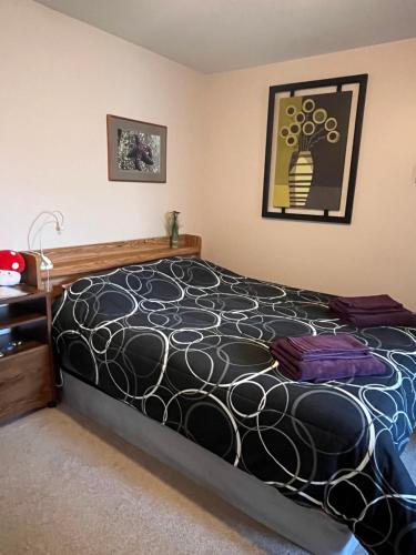 a bedroom with a bed with a black and white comforter at Serenity Bed and Breakfast in Comox