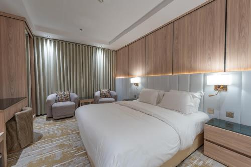 a hotel room with a large bed and two chairs at السهم الذهبي للشقق المخدومة in Taif