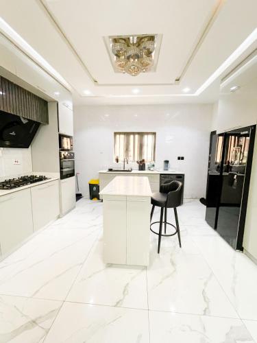 a white kitchen with a table and chairs in it at Nova Rise Apartment - Large 3BR with Wifi PS5 247 Power Smart TV in Lekki