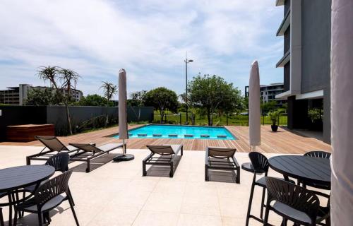 a patio with tables and chairs next to a pool at The Gateway Getaway in Durban