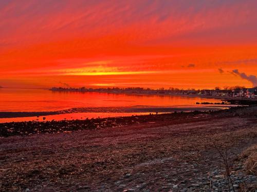 a sunset on the beach with a red sky at Dog-Friendly Oceanfront Getaway - Walk to Dining - Private Beach Access in Milford