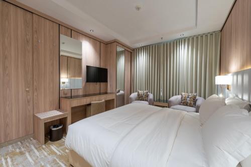 a bedroom with a large white bed and a television at السهم الذهبي للشقق المخدومة in Taif