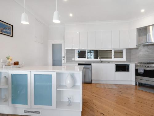 a kitchen with white cabinets and a white counter top at Oceanfront Beauty in Lilli Pilli in Surf Beach