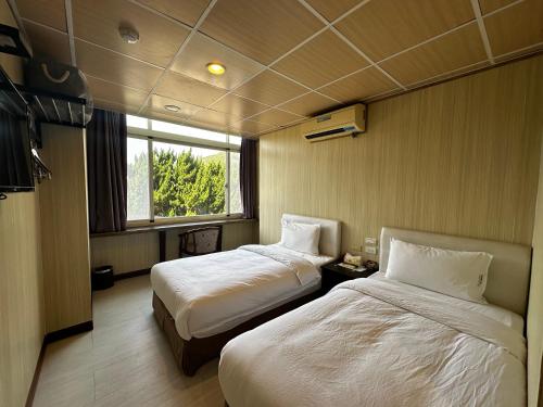 a hotel room with two beds and a window at 卡蹓英雄館 in Ma-tsu