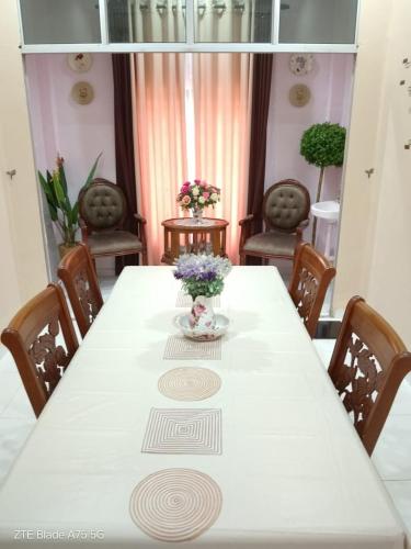 a white table with flowers in a room with chairs at Homestay Noor Mak Lagam in Kemaman