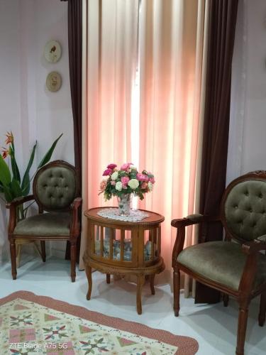 a vase of flowers on a table with two chairs at Homestay Noor Mak Lagam in Kemaman