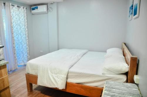 a bedroom with a bed with white sheets and a window at Dos Marias Tourist Inn Malapascua Island in Daanbantayan