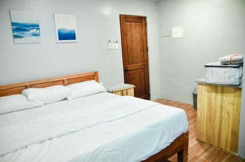 a bedroom with a white bed with a wooden headboard at Dos Marias Tourist Inn Malapascua Island in Daanbantayan