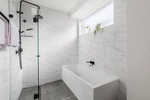 a white bathroom with a tub and a shower at Werribee Breeze - Carefree Stays near River & Dining in Werribee