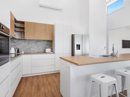 a white kitchen with white cabinets and wooden counters at Garden Bay Coastal Retreat in Malua Bay