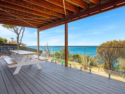 an open deck with a picnic table and the ocean at Garden Bay Coastal Retreat in Malua Bay