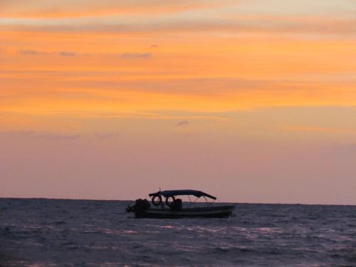 a small boat in the ocean at sunset at Casa Macondo RDM in San Onofre