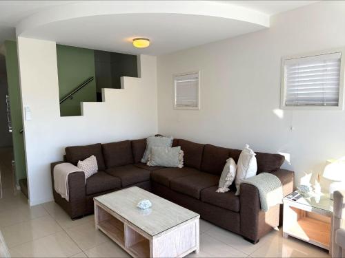 a living room with a brown couch and a table at 9 By the Clyde, Central Location in Batemans Bay in Batemans Bay