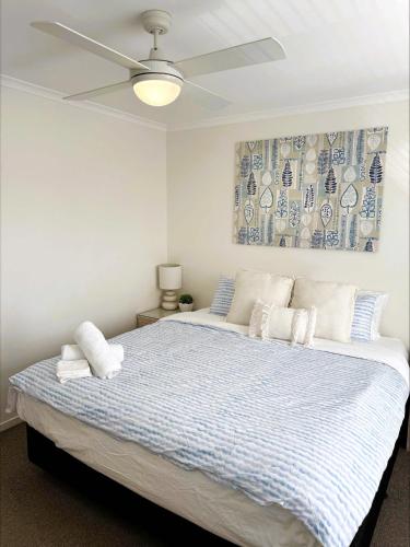 a bedroom with a large bed with a ceiling fan at 9 By the Clyde, Central Location in Batemans Bay in Batemans Bay