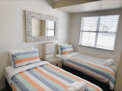 two beds in a small room with a mirror at 9 By the Clyde, Central Location in Batemans Bay in Batemans Bay