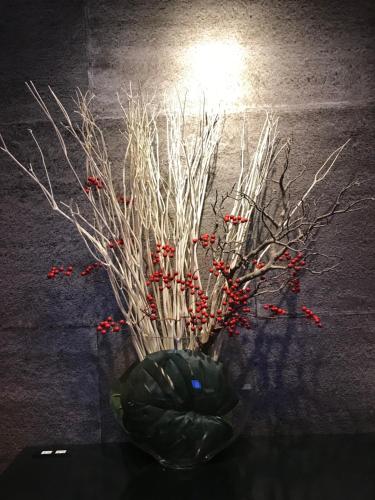 a vase filled with branches and red berries at Kyoto Shinmachi Rokkaku Hotel grandereverie in Kyoto
