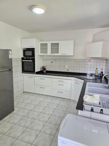 a kitchen with white cabinets and black appliances at Villa Mare Café ROG in Le Gosier