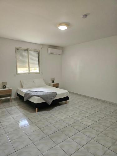 a white room with a bed and a window at Villa Mare Café ROG in Le Gosier