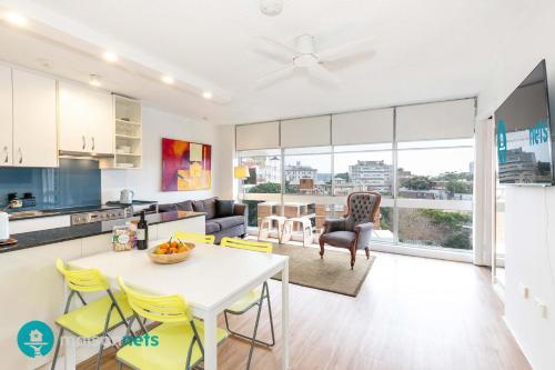 a kitchen and living room with a table and yellow chairs at Light Filled 1BR Retreat with Car Park & Pool in Sydney