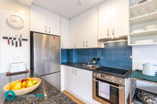 a kitchen with white cabinets and a bowl of fruit on the counter at Light Filled 1BR Retreat with Car Park & Pool in Sydney