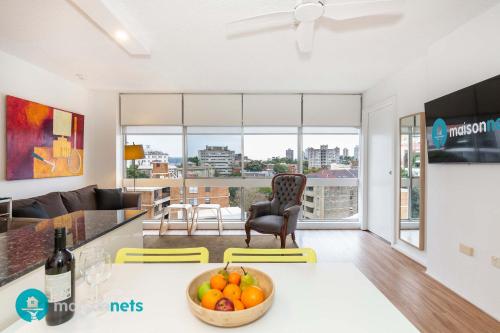 a kitchen and living room with a bowl of fruit on a table at Light Filled 1BR Retreat with Car Park & Pool in Sydney