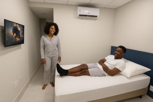 a woman standing next to a bed with a man at Hotel Soberano Brasília l SLEEP HOTÉIS in Taguatinga